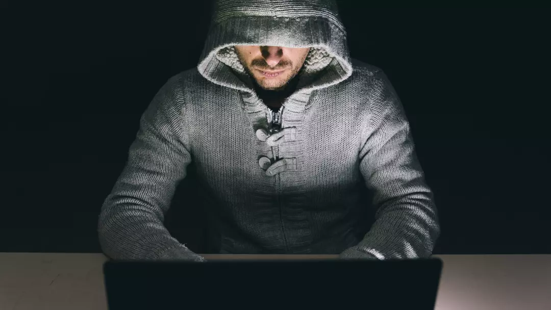 man working on dark web doing something illegal hiding face